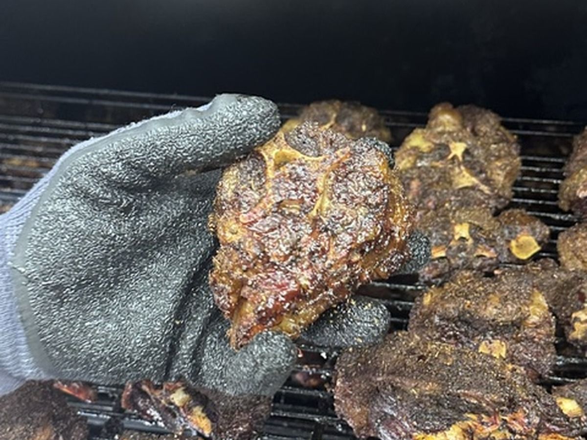 Smoked meat fresh off the grill, held in a gloved hand